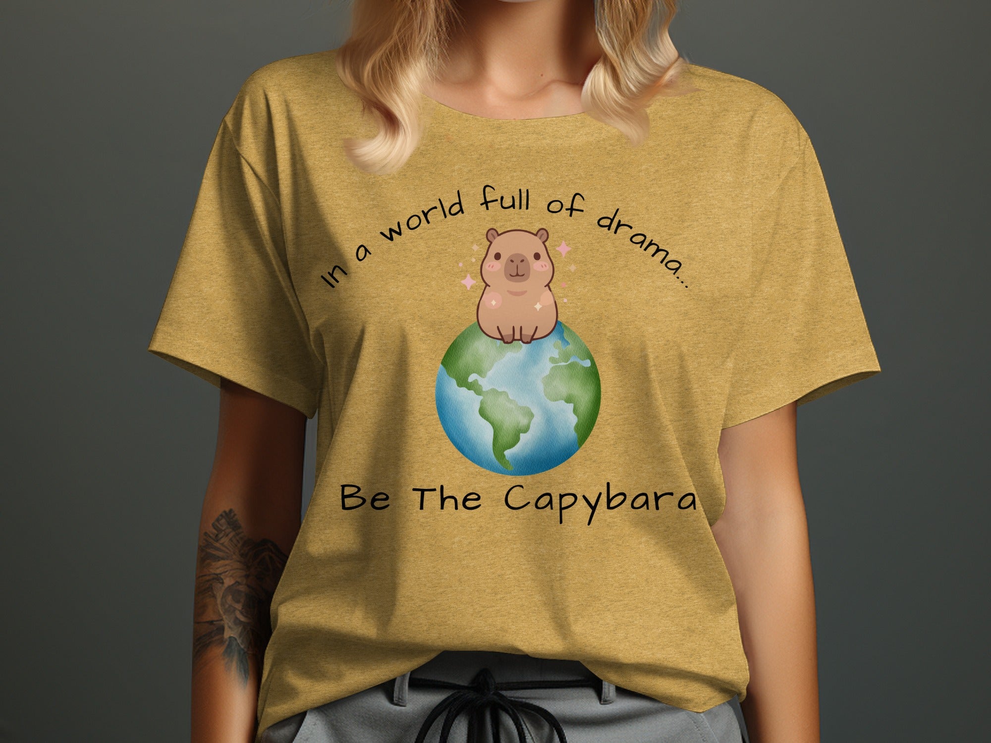 Yellow t-shirt with text "In a world full of drama... Be The Capybara" and a capybara on the Earth.