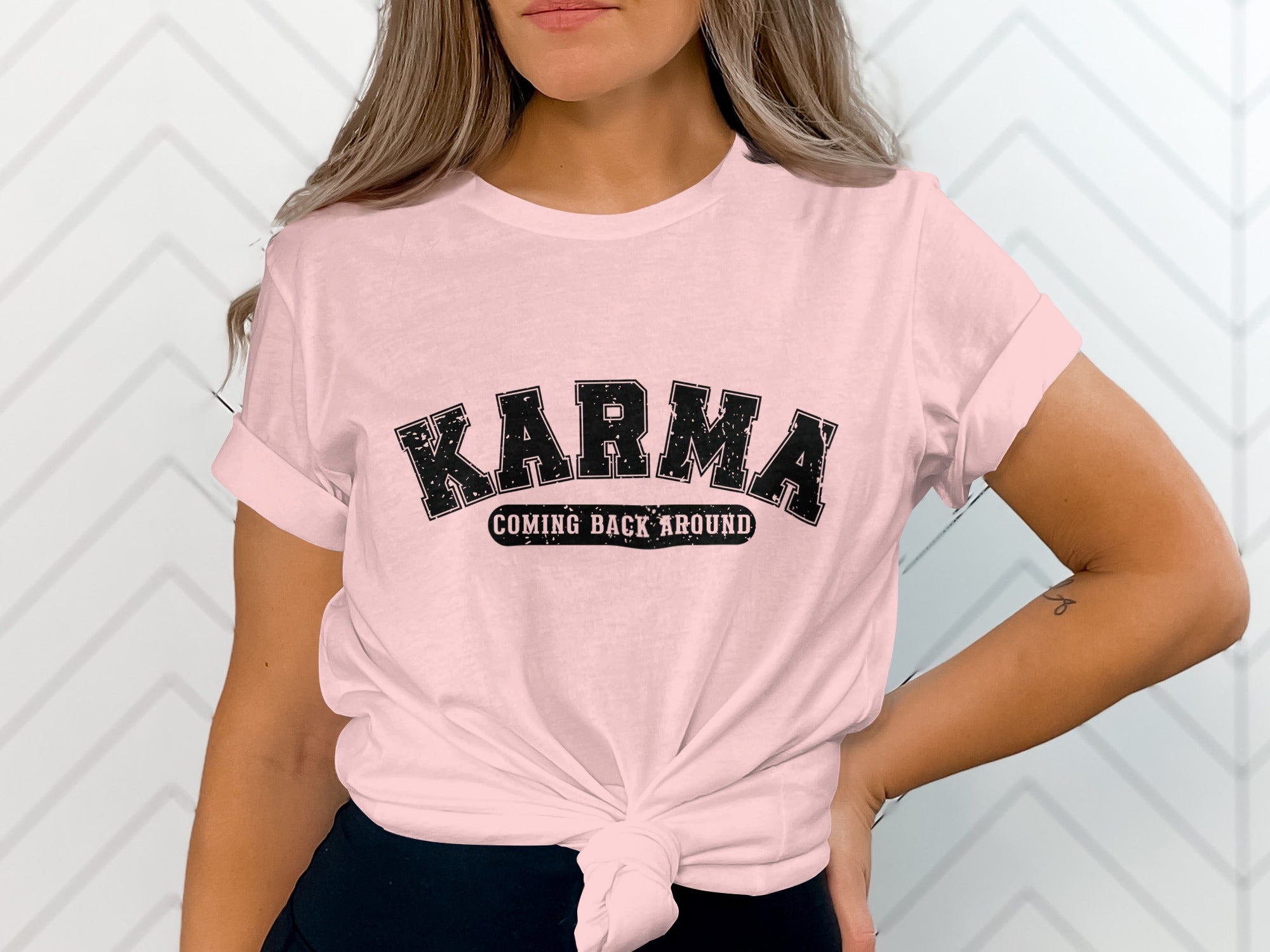 Pink t-shirt with black text "KARMA COMING BACK AROUND," tied at waist.