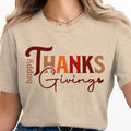 Happy Thanks Giving text graphic on a tan t-shirt worn by a woman.