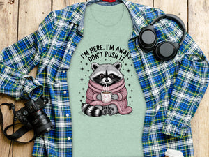 T-shirt with a raccoon holding a cup, text "I'm here, I'm awake, don't push it."