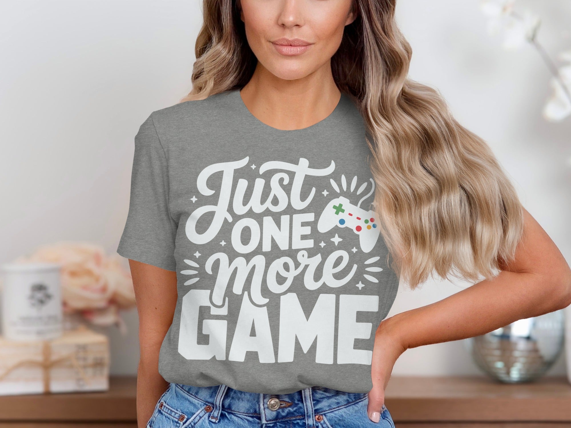 Grey t-shirt with white text that reads "Just one more GAME" and a video game controller.