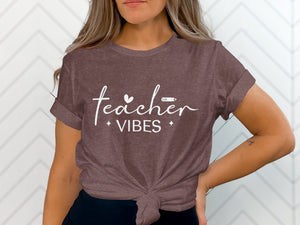 Brown t-shirt with "teacher vibes" text and heart and pencil graphics.