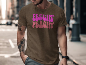 Brown t-shirt with "Feelin' Peachy" graphic in pink and purple wavy font.