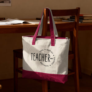 White canvas tote bag with "TEACHER" and inspirational words, hanging on a wooden chair.