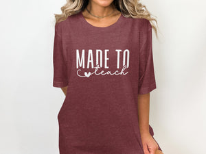 Maroon t-shirt with white text "MADE TO teach" and a heart detail.