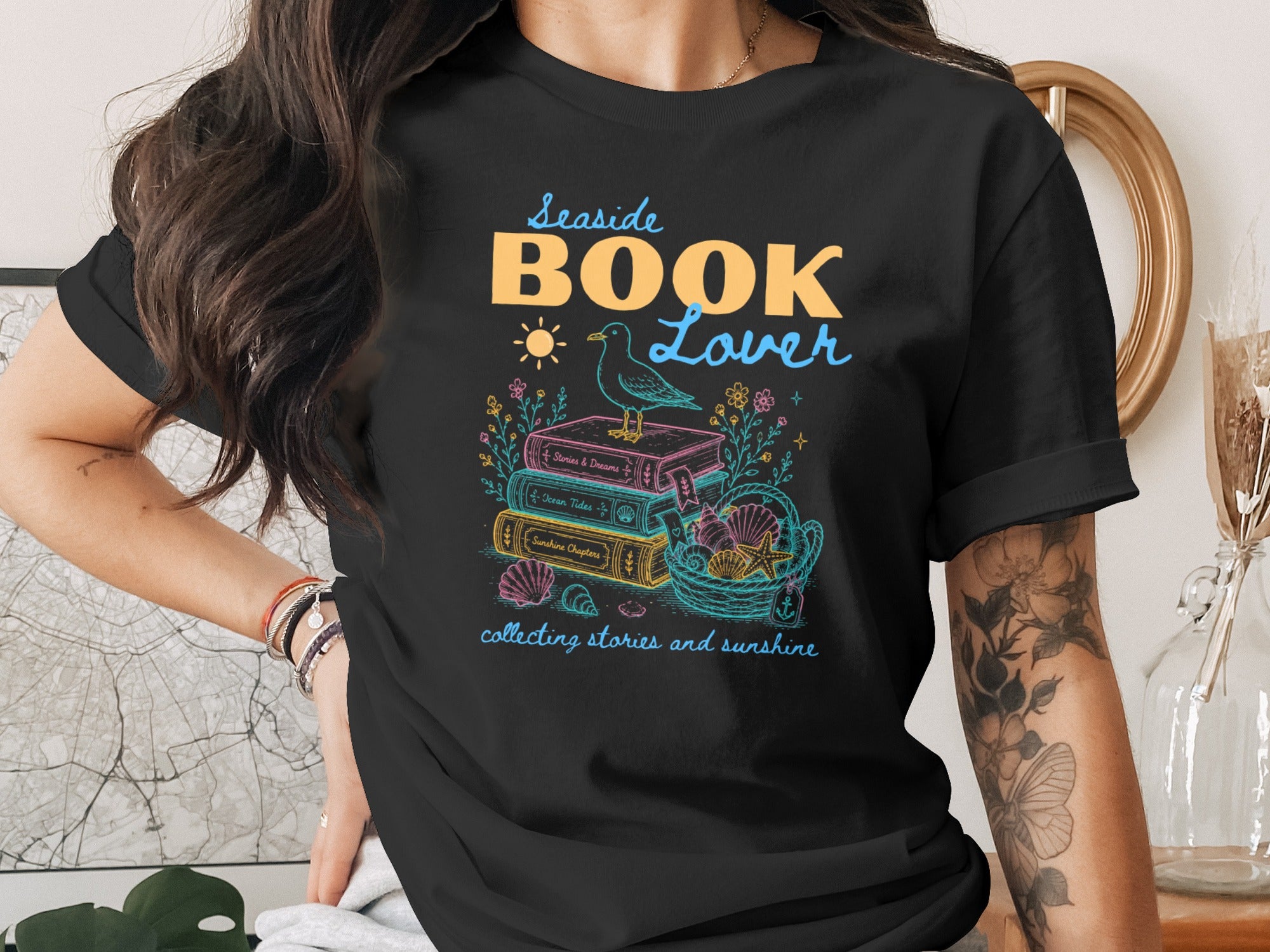 Black t-shirt with "Seaside BOOK Lover" text, books, shells, and a bird.