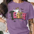 Purple t-shirt with "TEACH" text, ghost, coffee cup, bats, and spider.