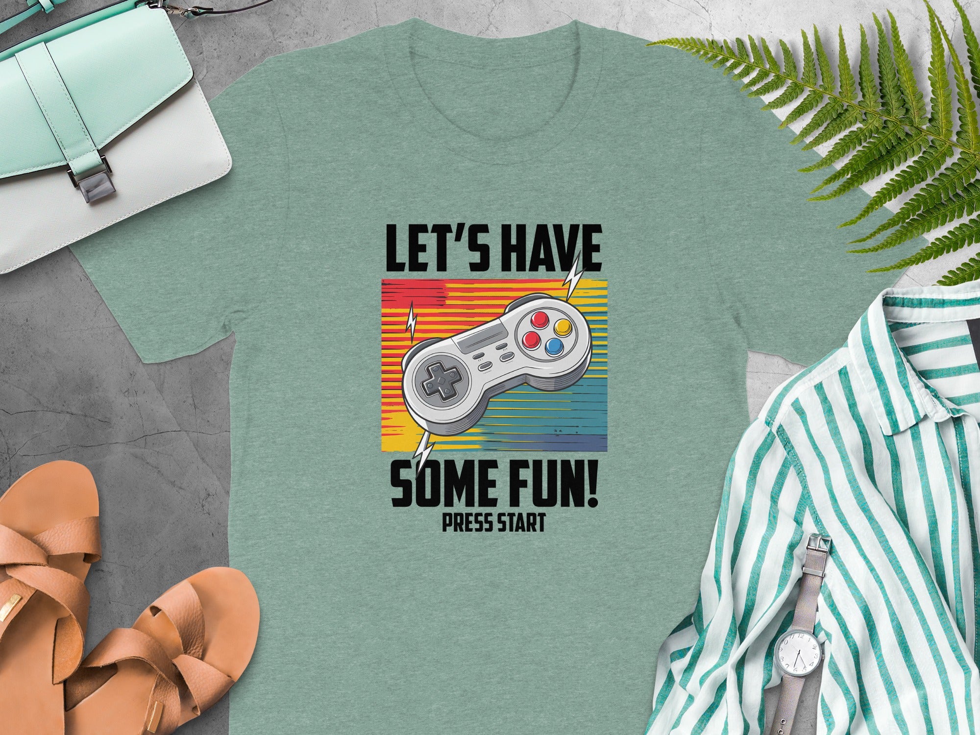 T-shirt with text "LET'S HAVE SOME FUN! PRESS START" and a video game controller.