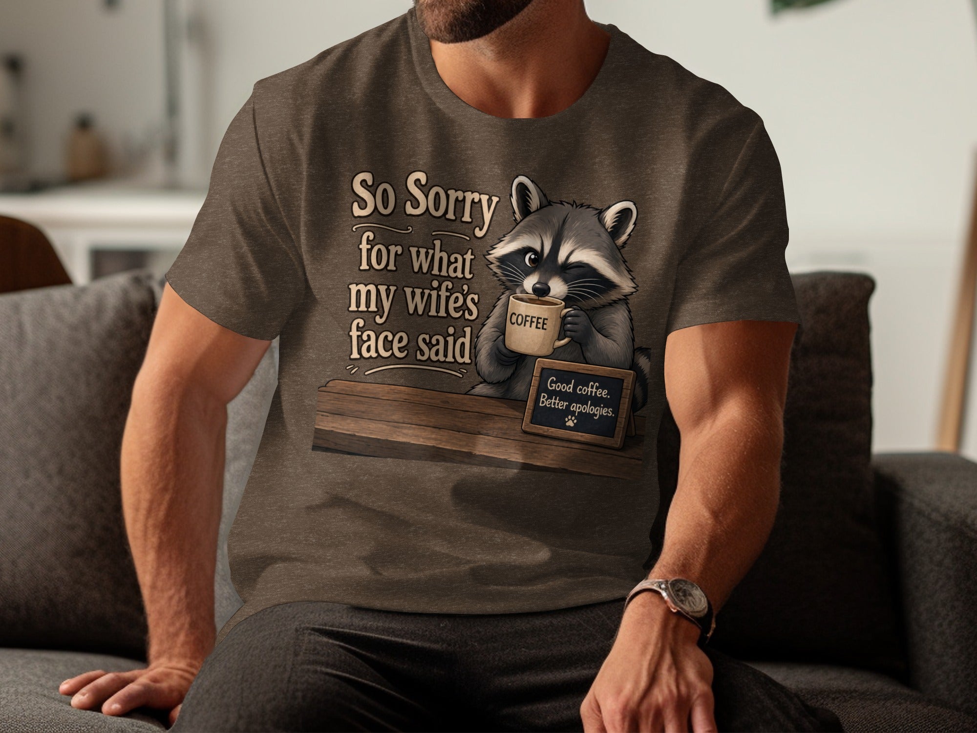 T-shirt graphic with raccoon holding coffee and text "So Sorry for what my wife's face said".