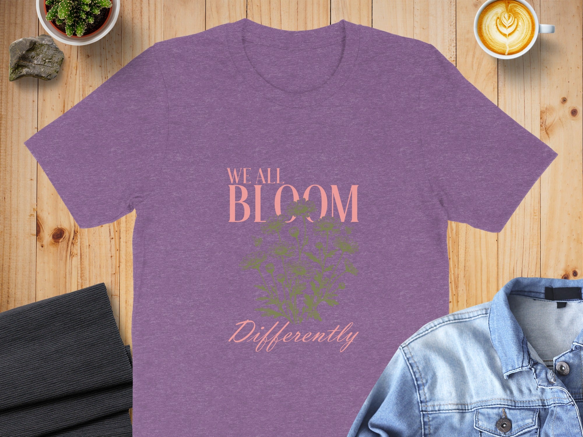 Purple t-shirt with "We All Bloom Differently" text and floral graphic.