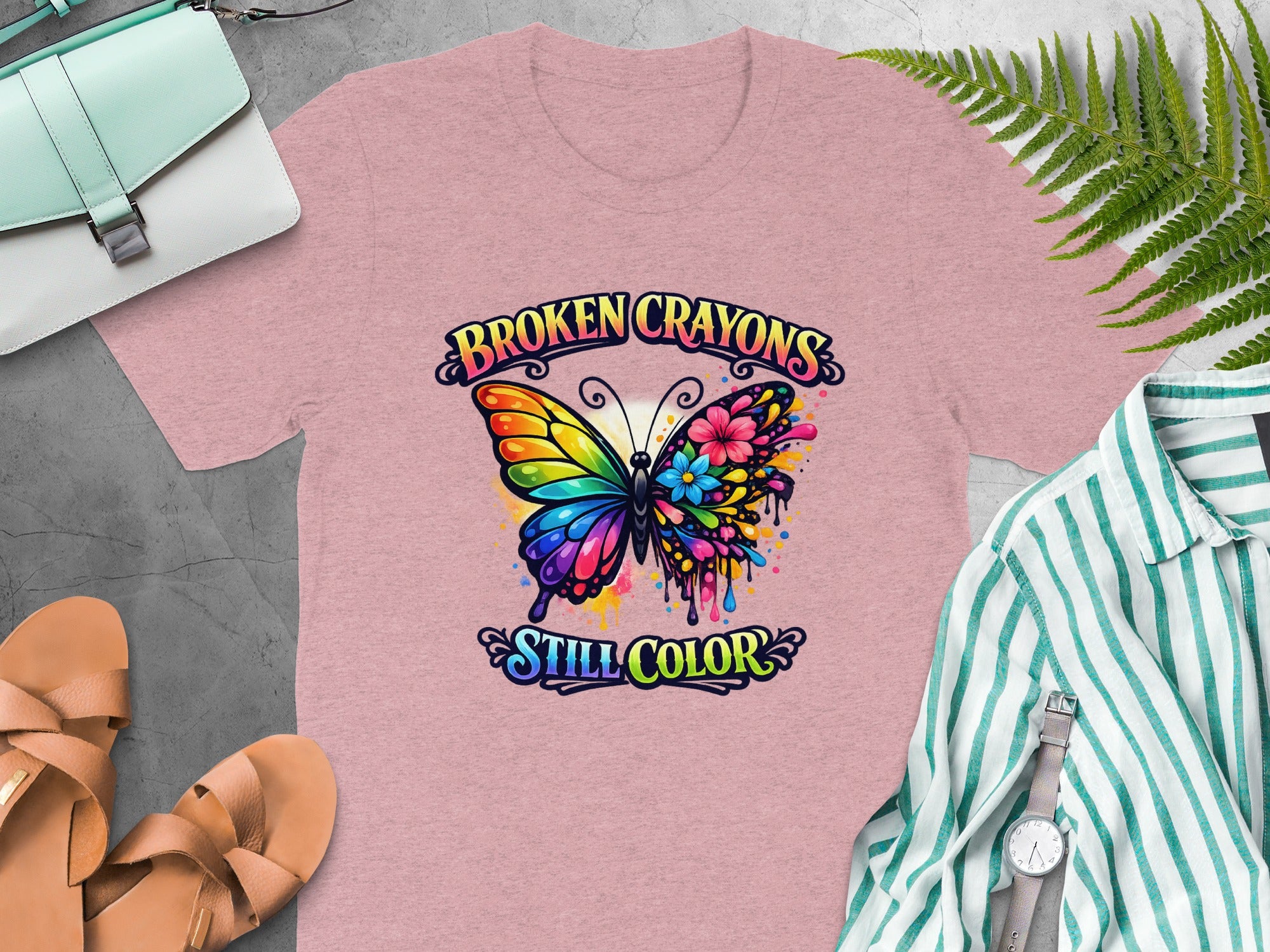Pink t-shirt with colorful butterfly graphic and text "BROKEN CRAYONS STILL COLOR".