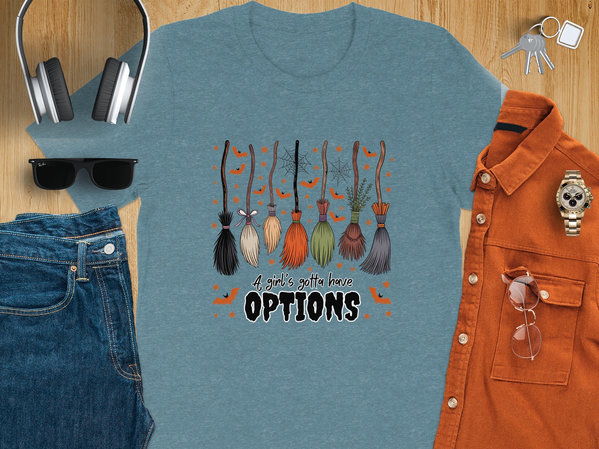Teal t-shirt with cartoon brooms and text "A girl's gotta have OPTIONS."