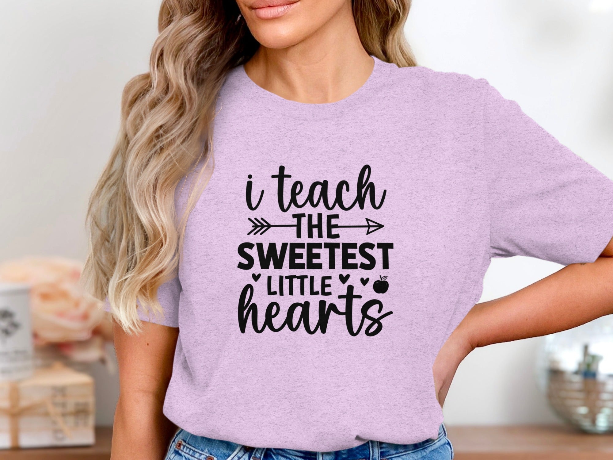 Light purple t-shirt with black text reading "i teach THE SWEETEST LITTLE hearts".