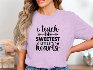 Light purple t-shirt with black text reading "i teach THE SWEETEST LITTLE hearts".