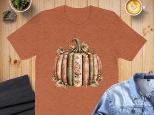 Orange t-shirt featuring a pumpkin design made of vintage books with floral accents.