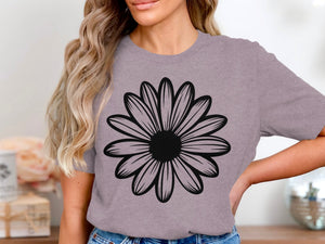 A woman wears a lavender t-shirt with a large black daisy graphic.