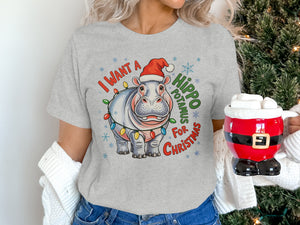 Grey t-shirt with a cartoon hippo wearing a Santa hat and Christmas lights, text "I WANT A HIPPOPOTAMUS FOR CHRISTMAS".