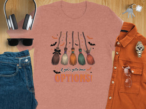 T-shirt with a graphic of five witch brooms and the text "A girl's gotta have OPTIONS!".