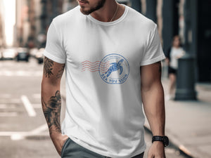 White t-shirt with circular blue stamp graphic featuring sea turtle and text.