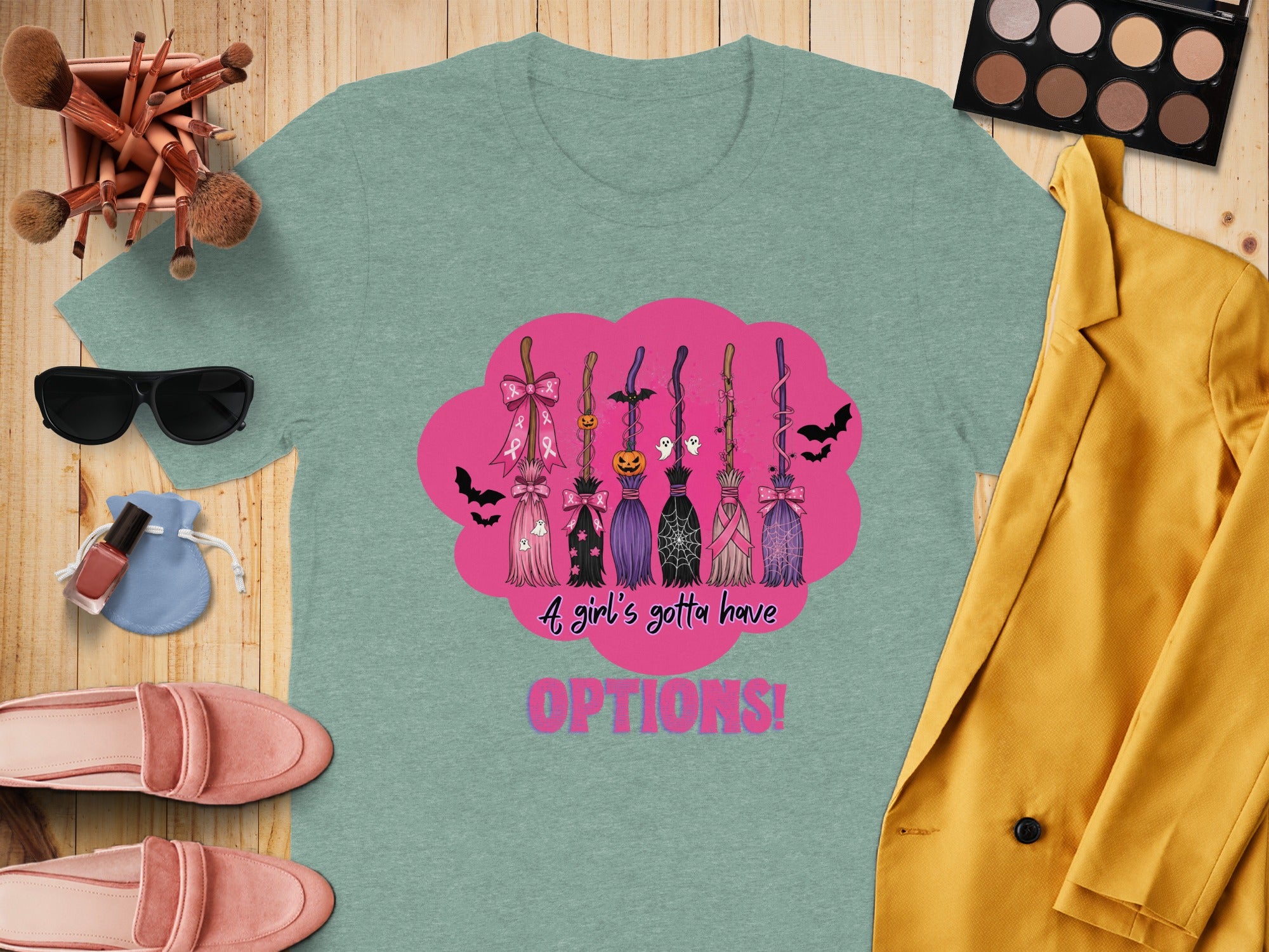 Teal t-shirt with Halloween-themed brooms and text "A girl's gotta have OPTIONS!".