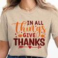 "In All Things Give Thanks" text with pumpkins and arrows on a tan shirt.