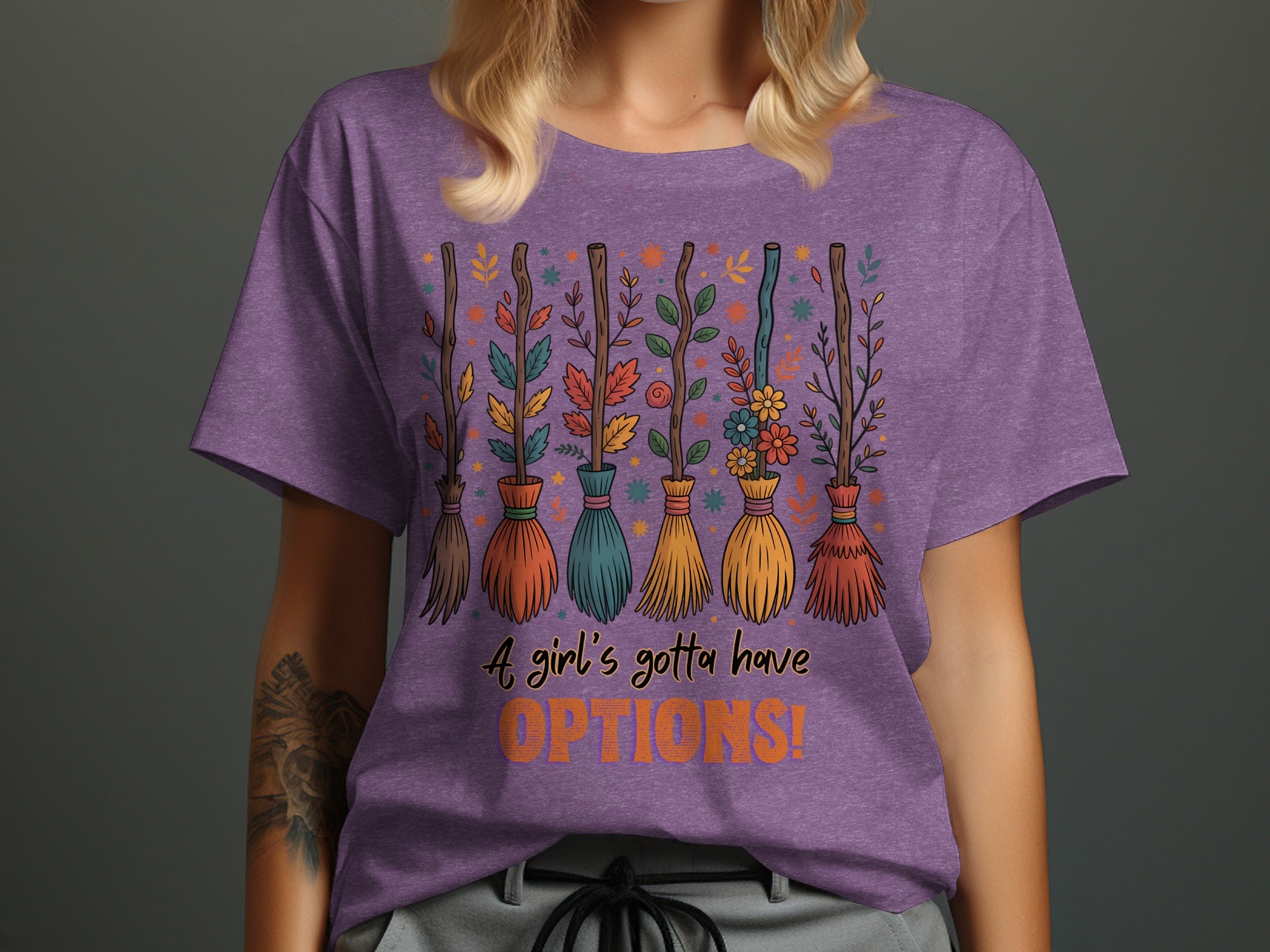 Purple t-shirt with brooms decorated with leaves and flowers. Text: "A girl's gotta have OPTIONS!"
