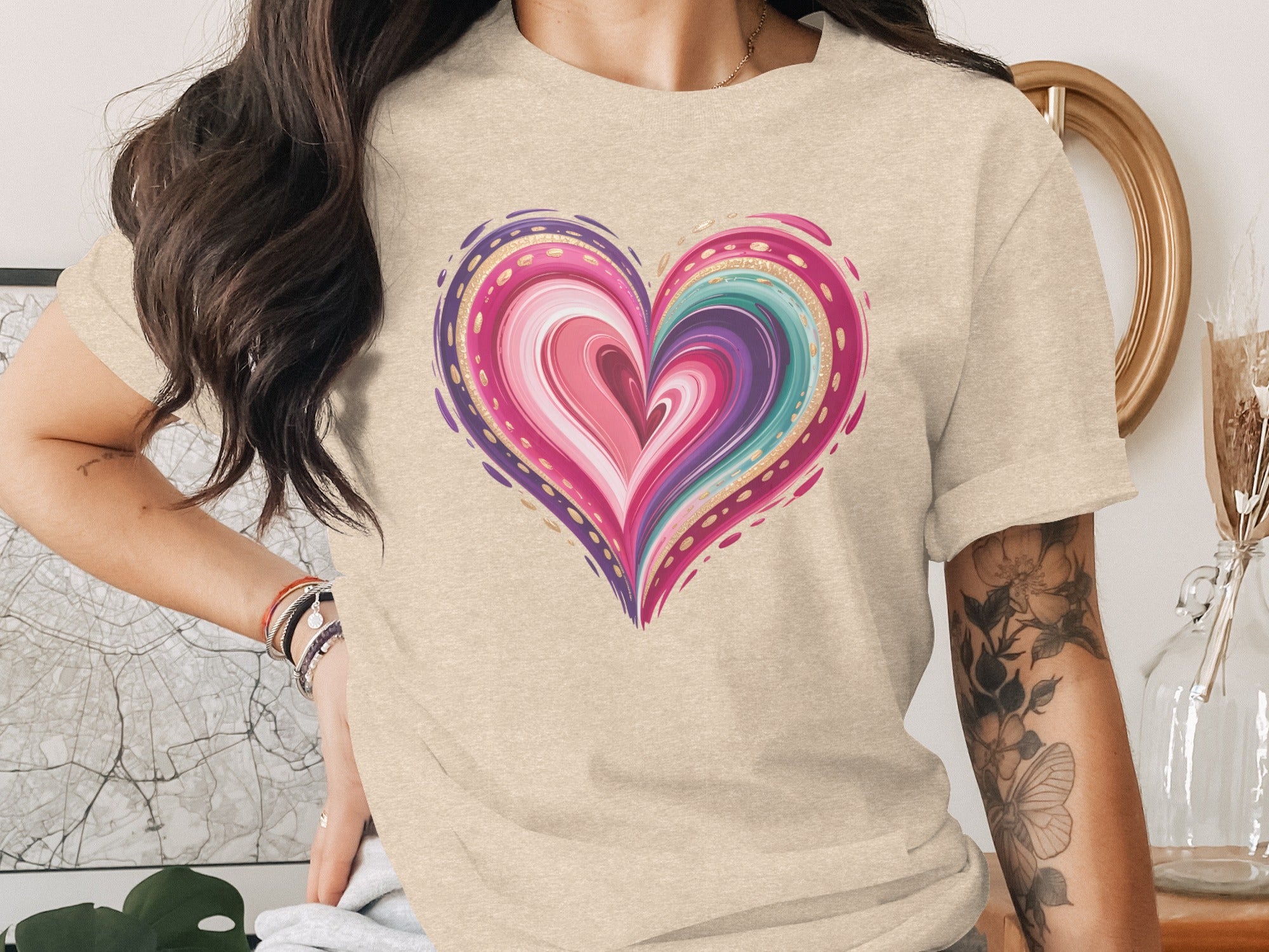 Beige t-shirt with a colorful, swirled heart graphic and gold accents.