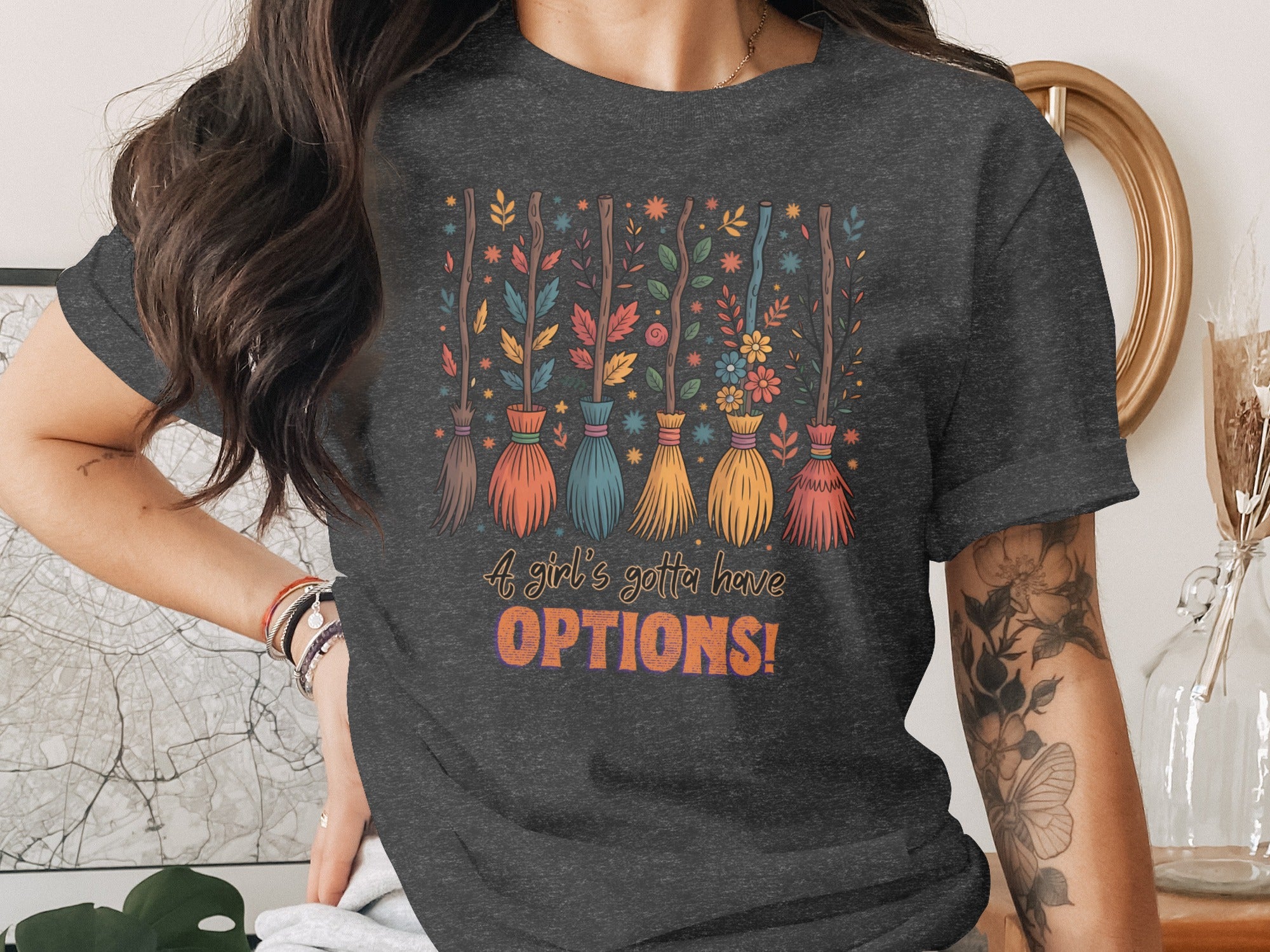 Dark t-shirt with colorful brooms and flowers, reads "A girl's gotta have OPTIONS!"
