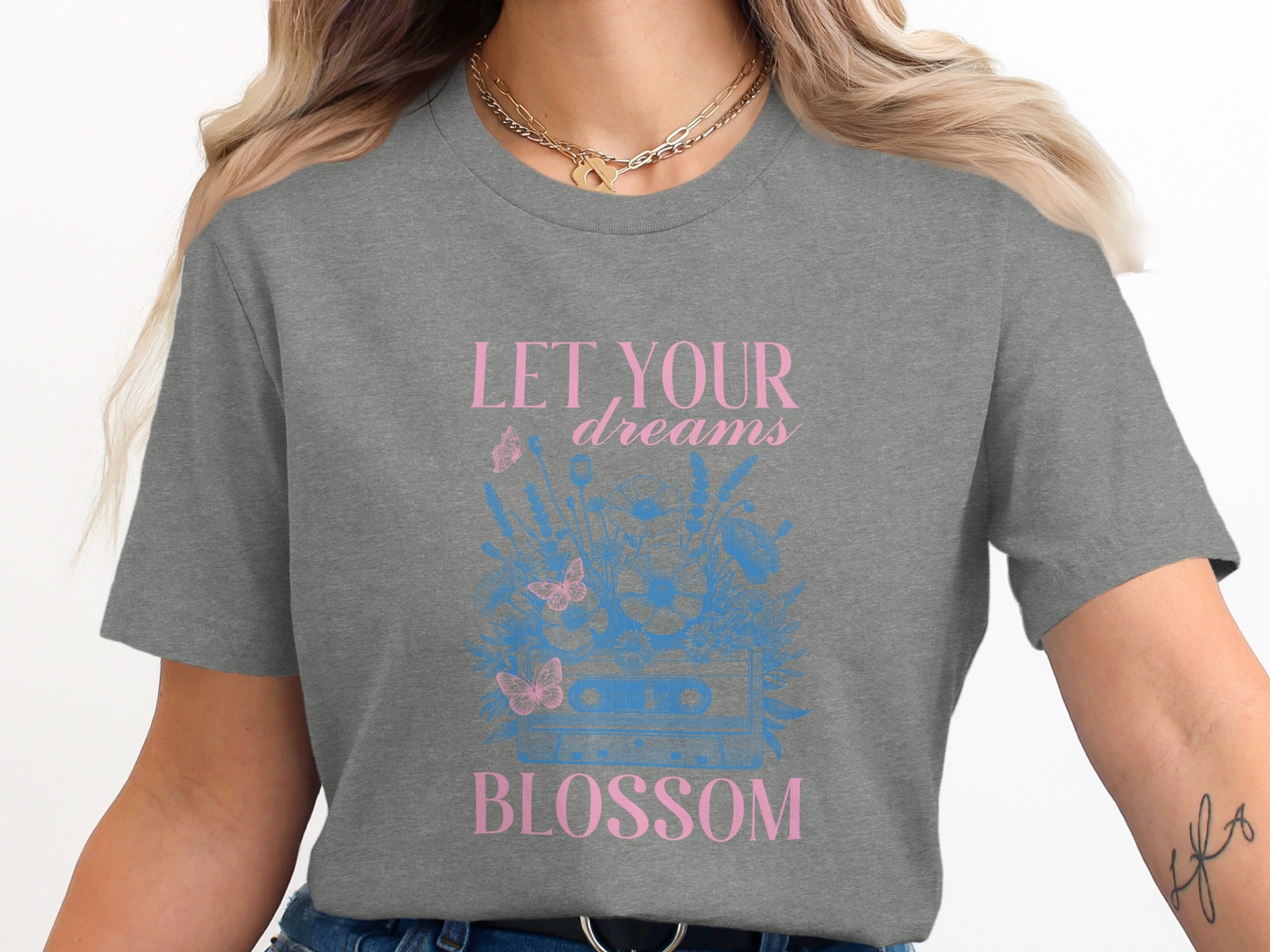 Grey t-shirt with pink text "LET YOUR dreams BLOSSOM" and blue floral cassette tape graphic.
