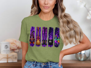 Witch hat, broom, striped stockings, cauldron, and potion bottles graphic on a green t-shirt.