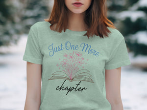 Light green t-shirt graphic with open book and "Just One More chapter" text.
