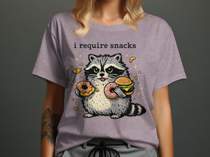 T-shirt with text "i require snacks" and a raccoon holding donuts and a burger.