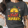 Taco graphic with text "It's Ok to Fall Apart" on dark grey t-shirt.