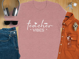 Rose pink t-shirt with "Teacher Vibes" text, headphones, jeans, keys, and watch.