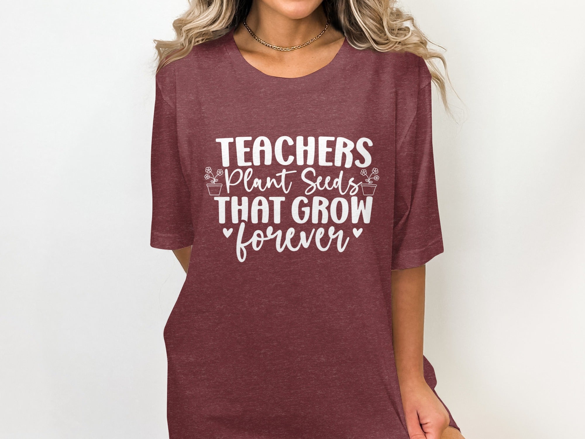 Maroon t-shirt on a person with white text: Teachers Plant Seeds That Grow Forever