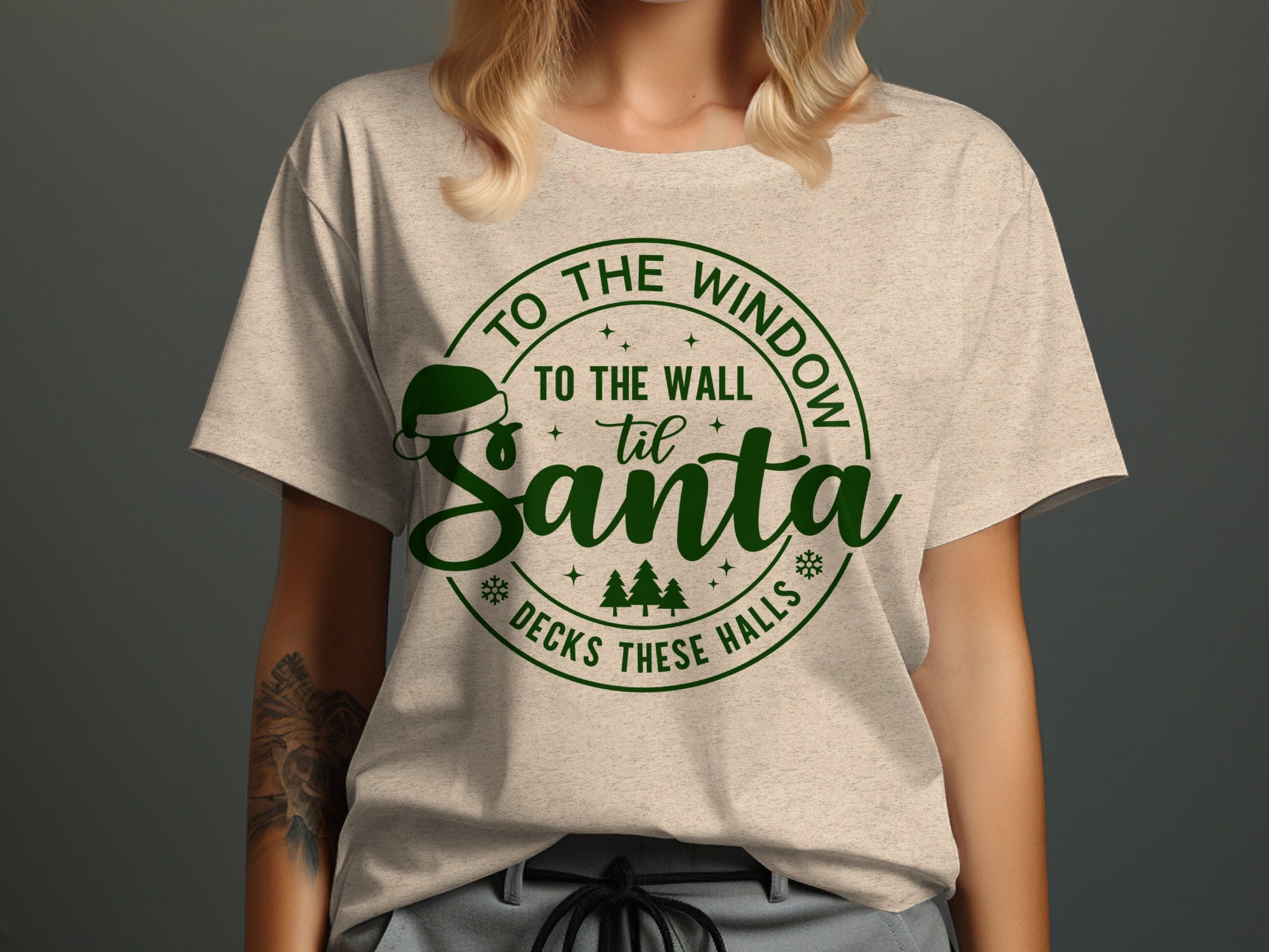 T-shirt with green text "To the window, to the wall, til Santa decks these halls".