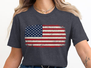 Distressed American flag graphic on a charcoal t-shirt worn by a person.