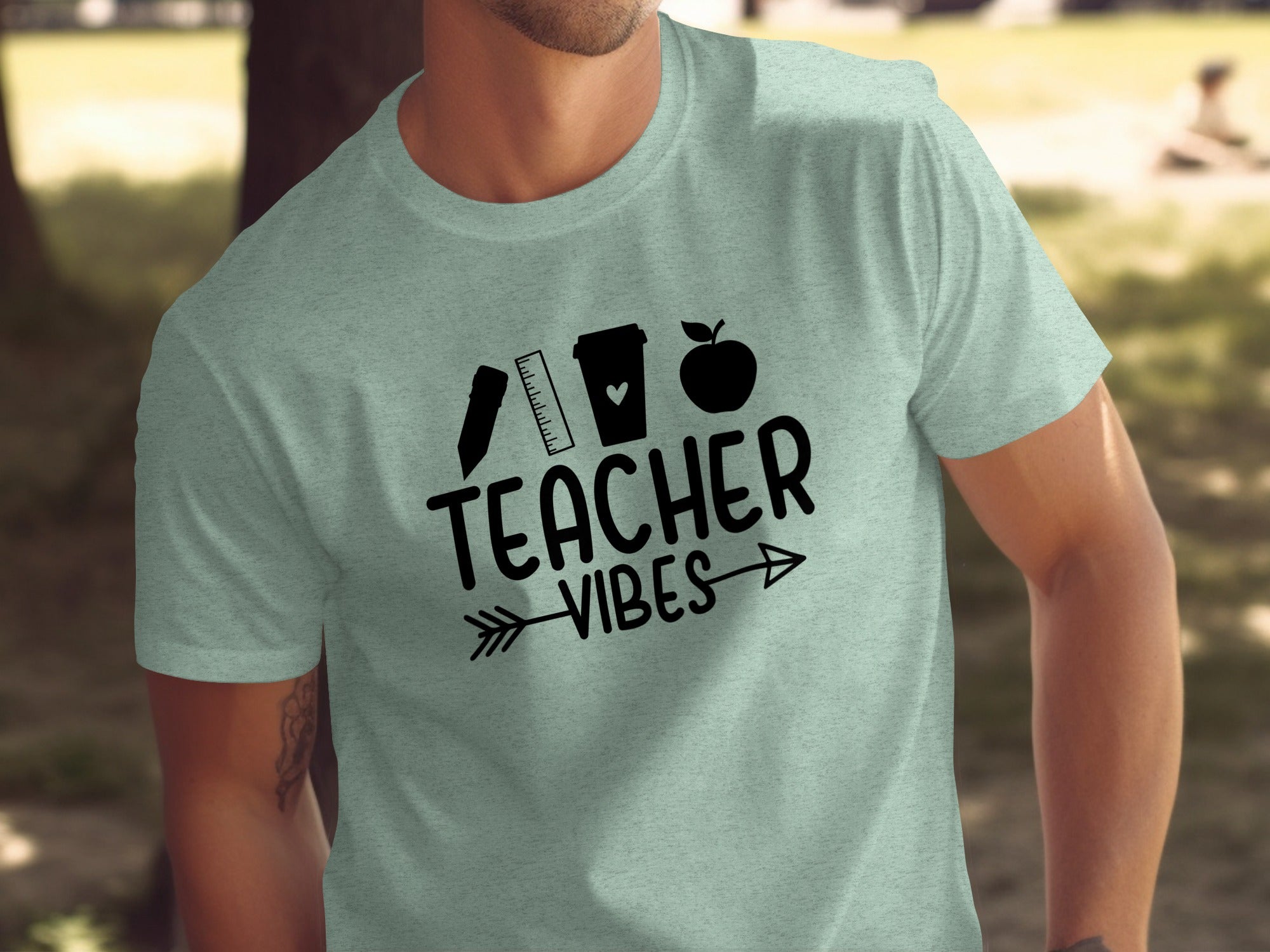 Light green t-shirt with black text and icons: "Teacher Vibes", ruler, coffee cup, apple.