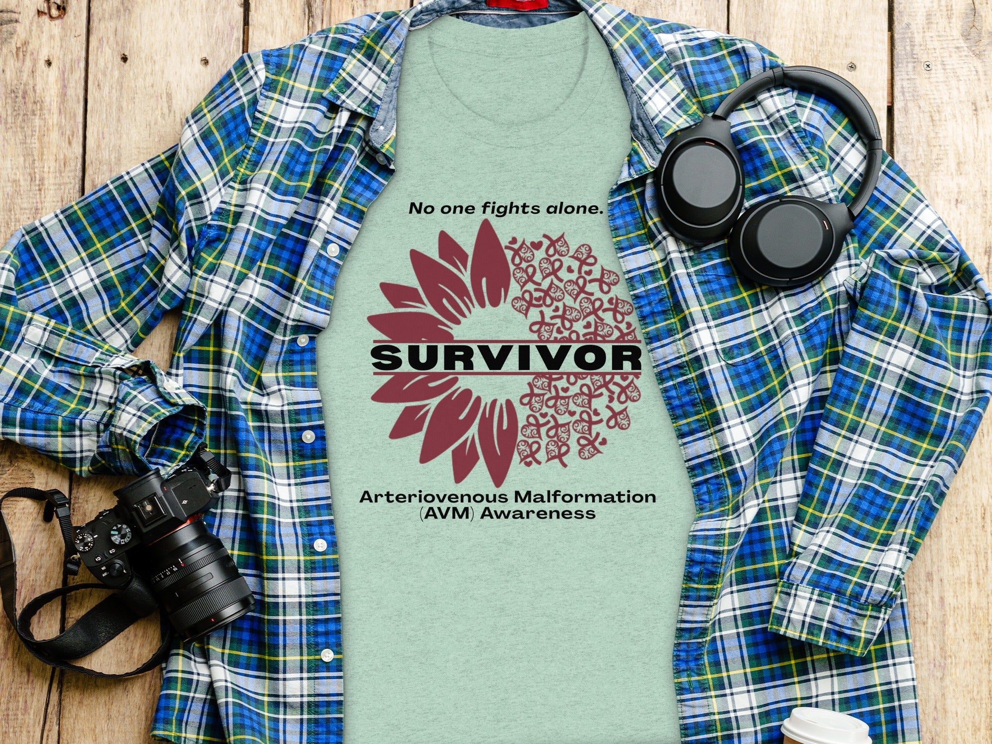 Light green t-shirt displaying a sunflower design with the word SURVIVOR and AVM Awareness text.