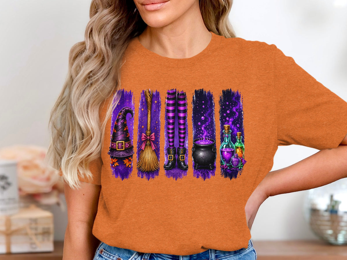 Halloween graphic of witch hat, broom, legs, cauldron, and potions on an orange shirt.
