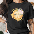 Black t-shirt with a sun face adorned with pink flowers and greenery graphic.