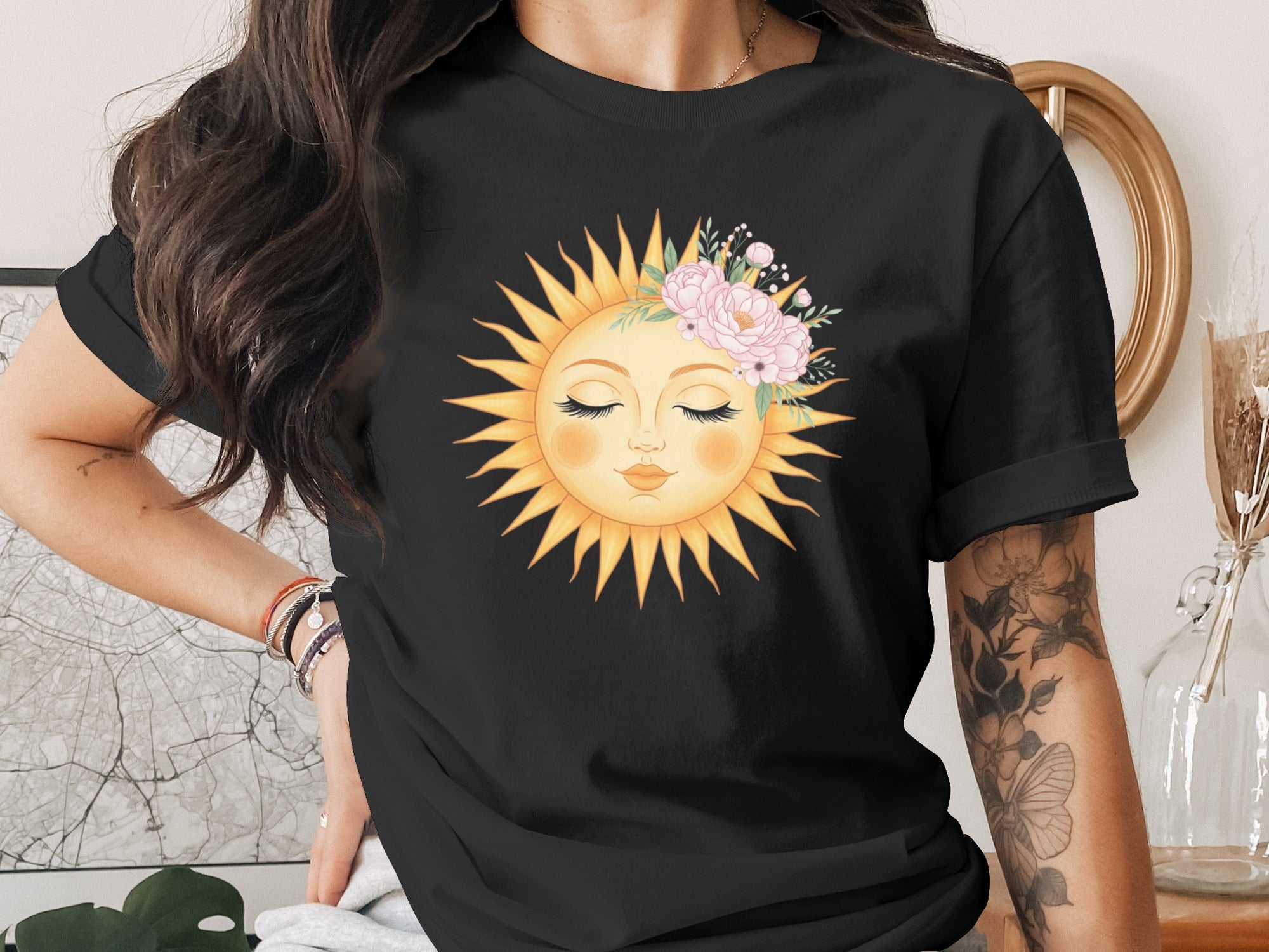 Black t-shirt with a sun face adorned with pink flowers and greenery graphic.