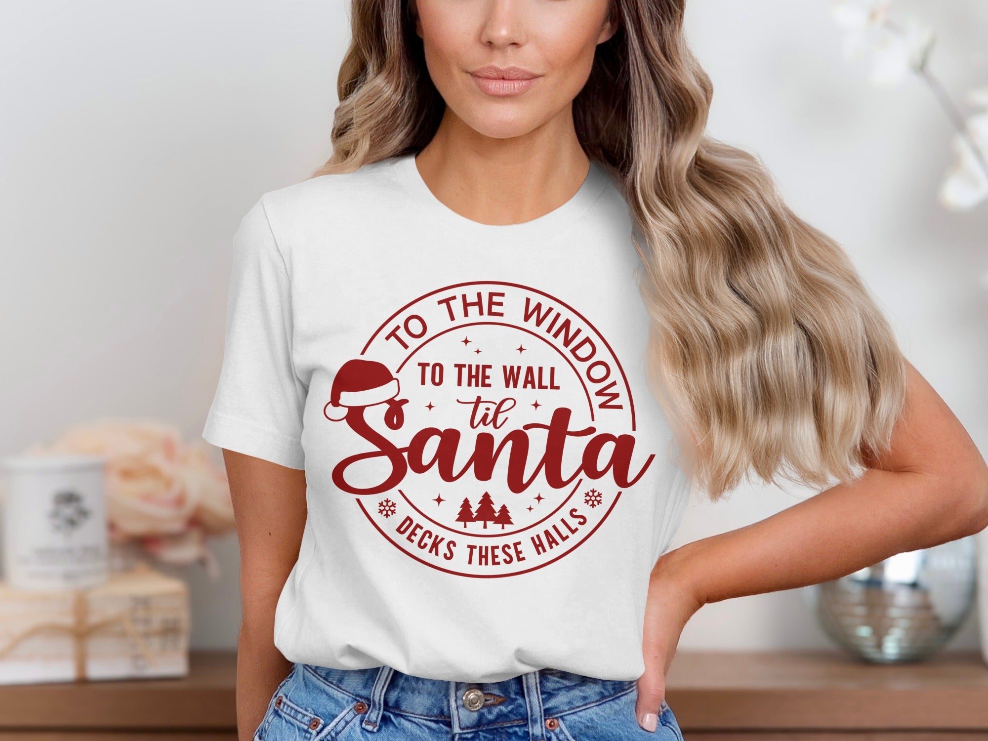 White t-shirt with red circular graphic: "To the window to the wall til Santa decks these halls"