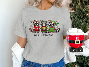 Three raccoons in festive Christmas attire with text "FERAL BUT FESTIVE."