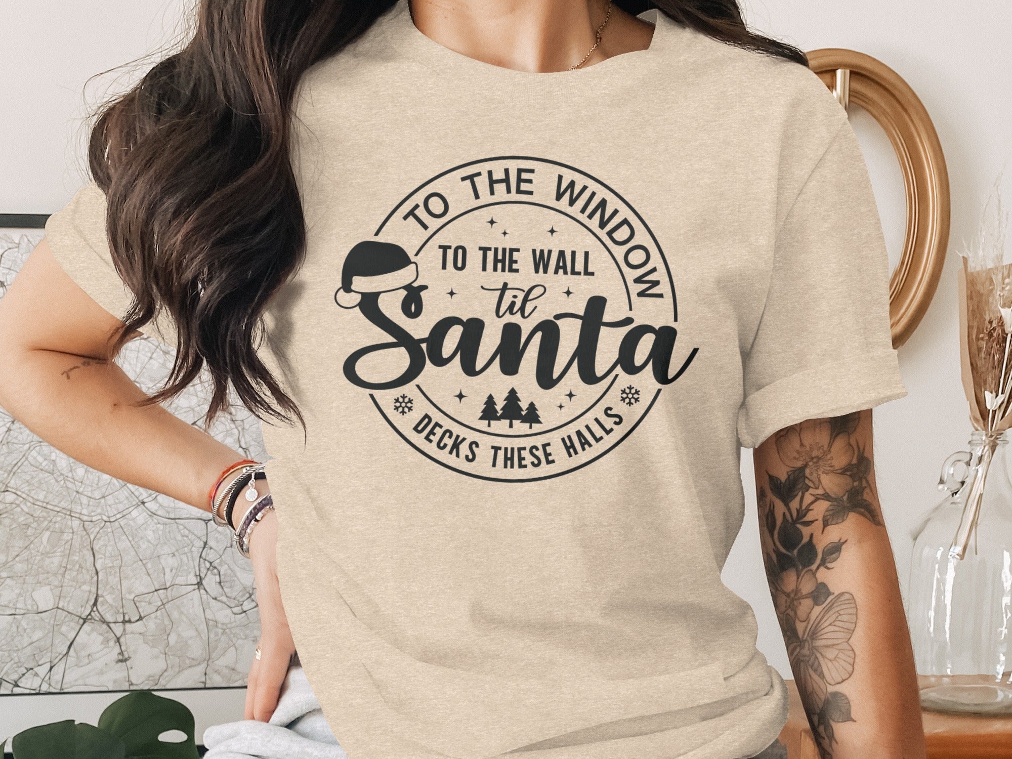 Cream t-shirt with "To the window to the wall 'til Santa decks these halls" Christmas graphic.