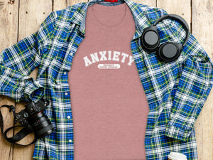Pink t-shirt with "ANXIETY UNIVERSITY HONORS PROGRAM" text, a plaid shirt, headphones, and camera.