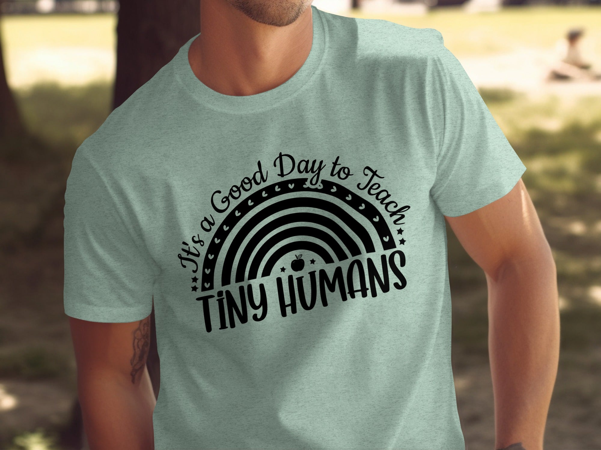 Light green t-shirt with black text "It's a Good Day to Teach Tiny Humans" and rainbow graphic.