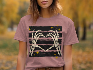 Skeleton hands form a heart shape on a dark striped background with yellow stars.