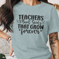 Light blue t-shirt with "Teachers Plant Seeds That Grow forever" black text and floral accents.
