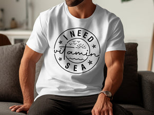 White t-shirt with "I NEED vitamin SEA" graphic and seaside elements.
